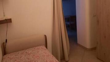 A bedroom with a bed, a lamp, and a wooden door.
