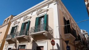 Un edificio con fachada clásica, contraventanas verdes y balcones ornamentados.