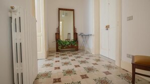 Un pasillo con baldosas de diseño, un radiador, un espejo y una puerta.