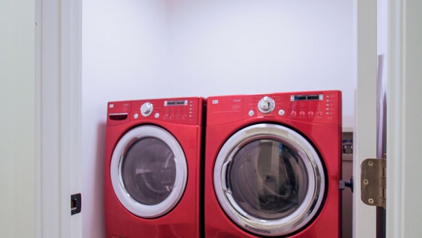 A compact laundry room with two red front-loading washing machines and a tiled floor. - Fall Family Retreat: Views, Tennis, Fireplace (Stowe)