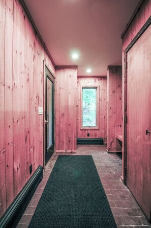 A hallway with wooden walls, a green carpet, and a window with a view of trees.