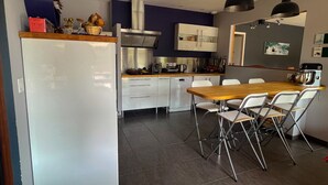 Una cocina moderna con armarios blancos, una campana extractora de acero inoxidable y una mesa de madera con cuatro sillas.
