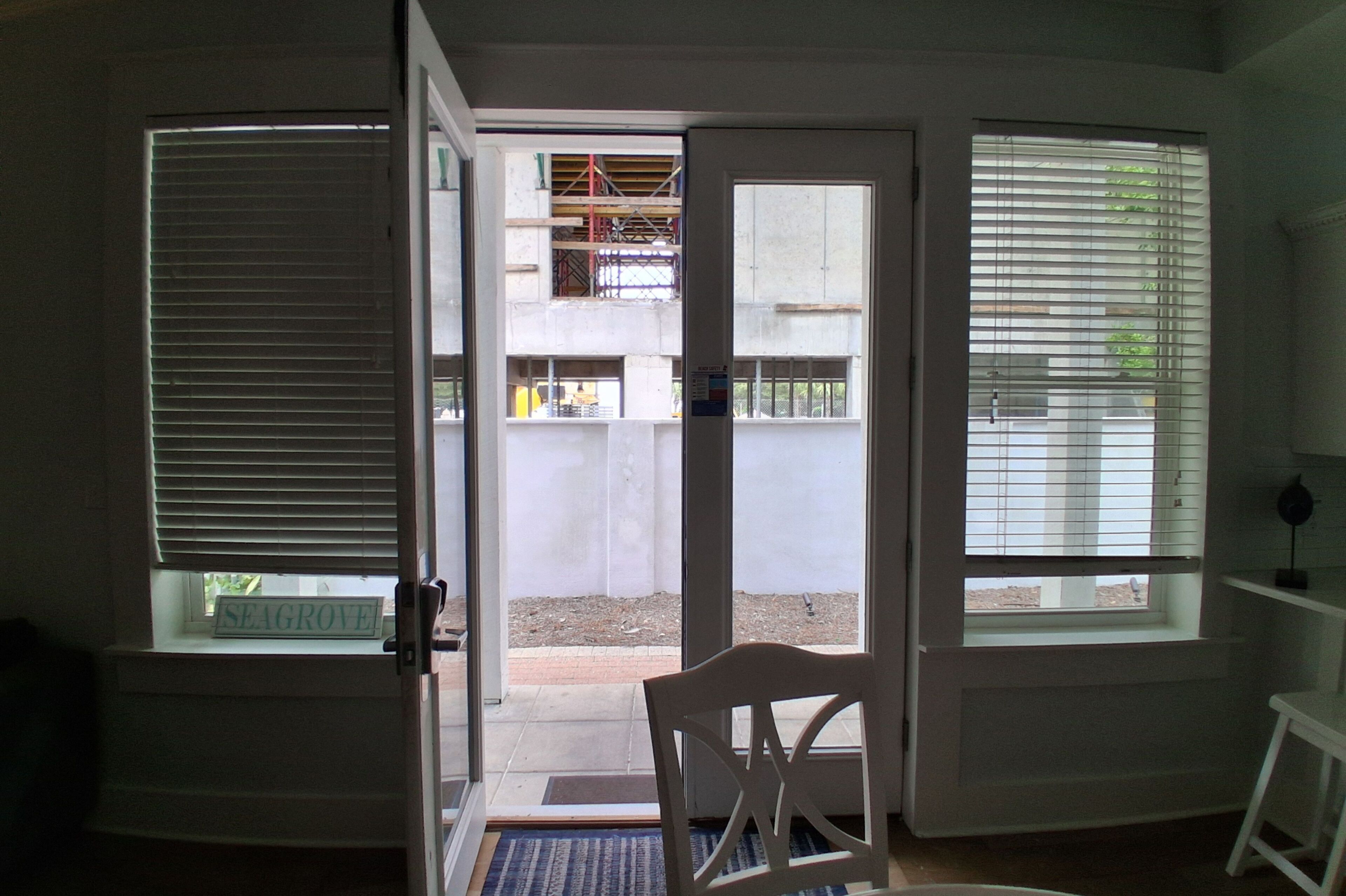 Et værelse med en skydedør, der fører til en balkon, en stol og et lille bord.
