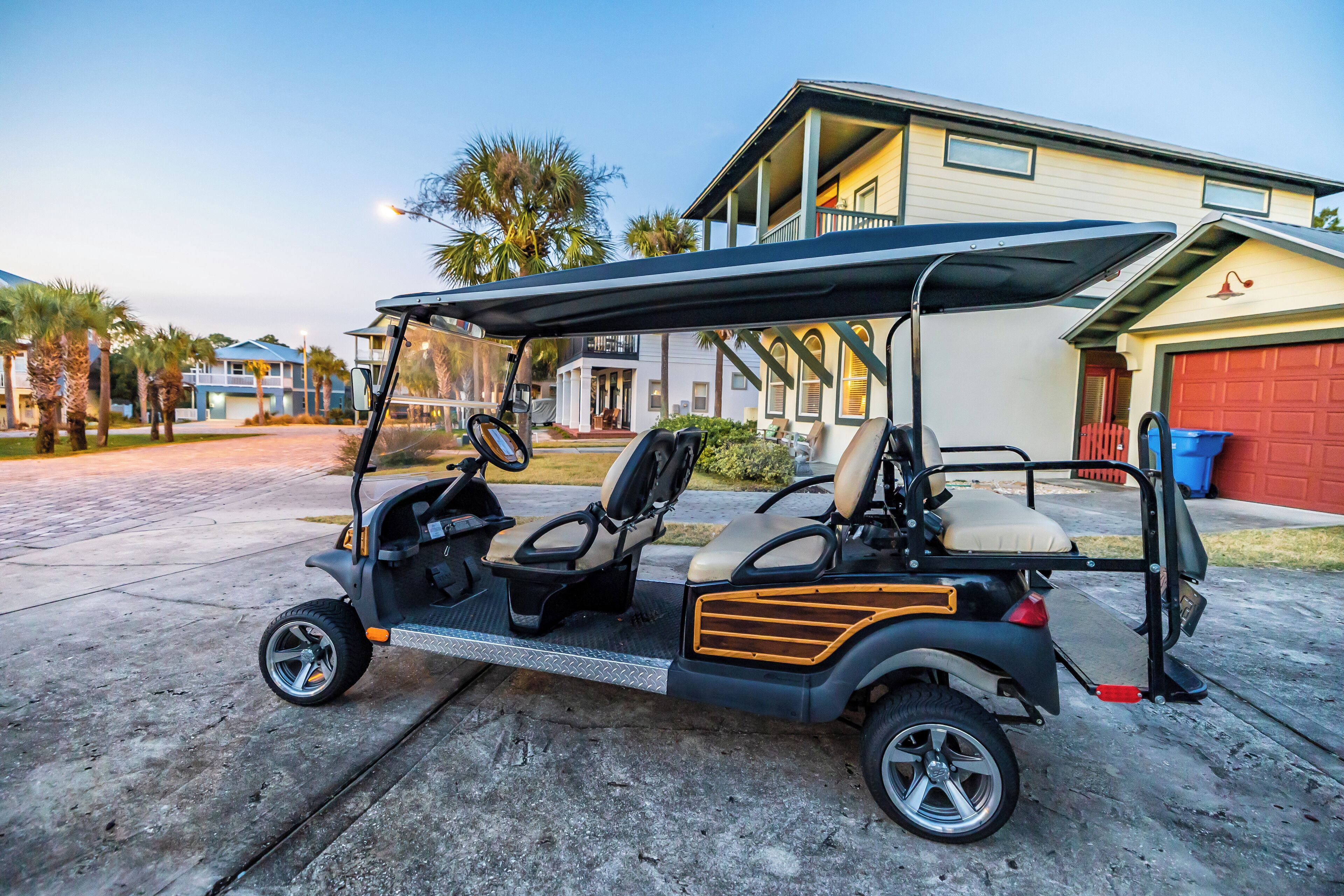 A golf cart parked on a driveway with a house in the background.