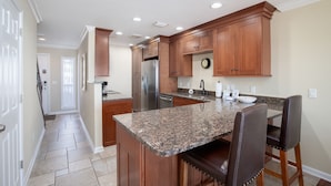 A kitchen with wooden cabinets, granite countertops, and stainless steel appliances. - Directly On The Beach! First Floor Sundeck! Near Pier Park! Sleeps 6! (Panama City Beach)