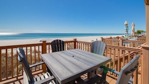 A wooden deck with a table and chairs overlooking a beach. - Directly On The Beach! First Floor Sundeck! Near Pier Park! Sleeps 6! (Panama City Beach)