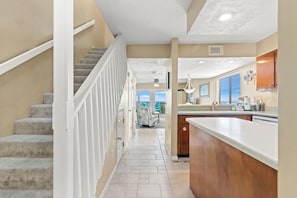 A hallway leading to a kitchen with a view, a staircase, and a dining area. - Breathtaking Views From Gulf Front 2 Bd / 3 Ba Townhome! (Panama City Beach)