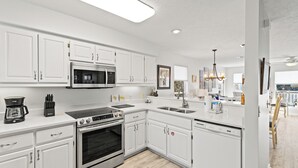 Una cocina moderna con armarios blancos, electrodomésticos de acero inoxidable y una luz superior brillante.