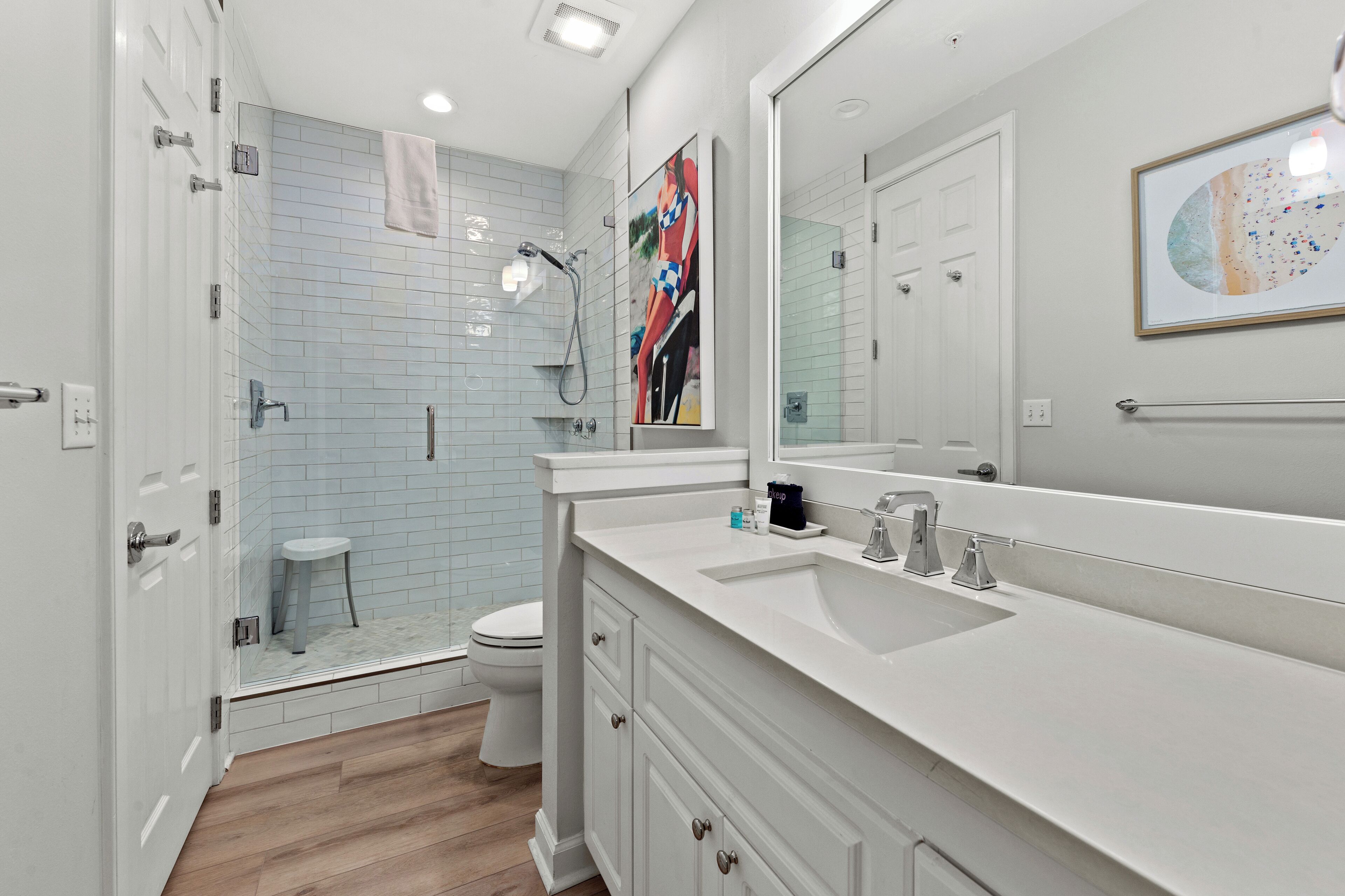 A modern bathroom with a walk-in shower, a toilet, and a large mirror.
