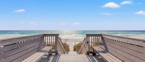 A wooden boardwalk leading to a beach with a clear view of the ocean.