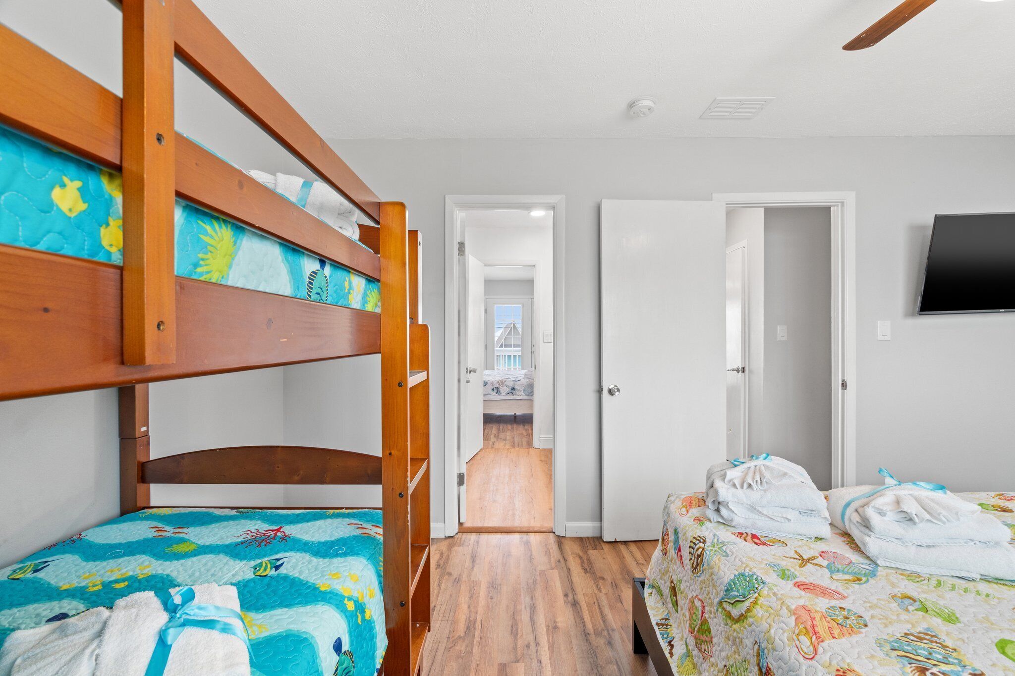 Dormitorio con literas, cabecero de madera, cama con colcha colorida y mesita de noche con toallas.