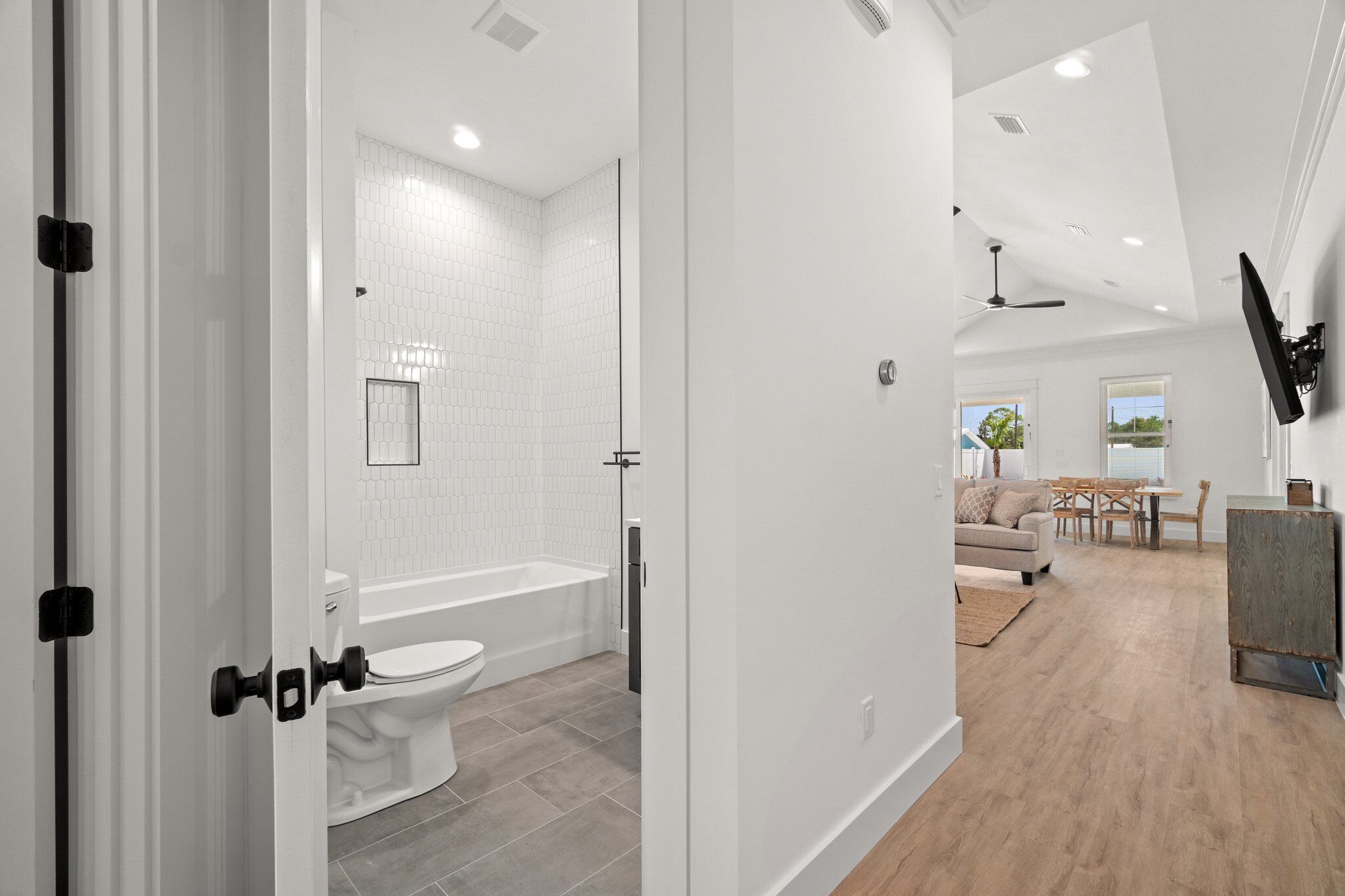 A modern bathroom with a toilet, bathtub, and white tiled walls.
