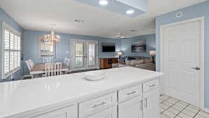 Una cocina moderna con armarios blancos, una isla grande y un comedor con candelabro.