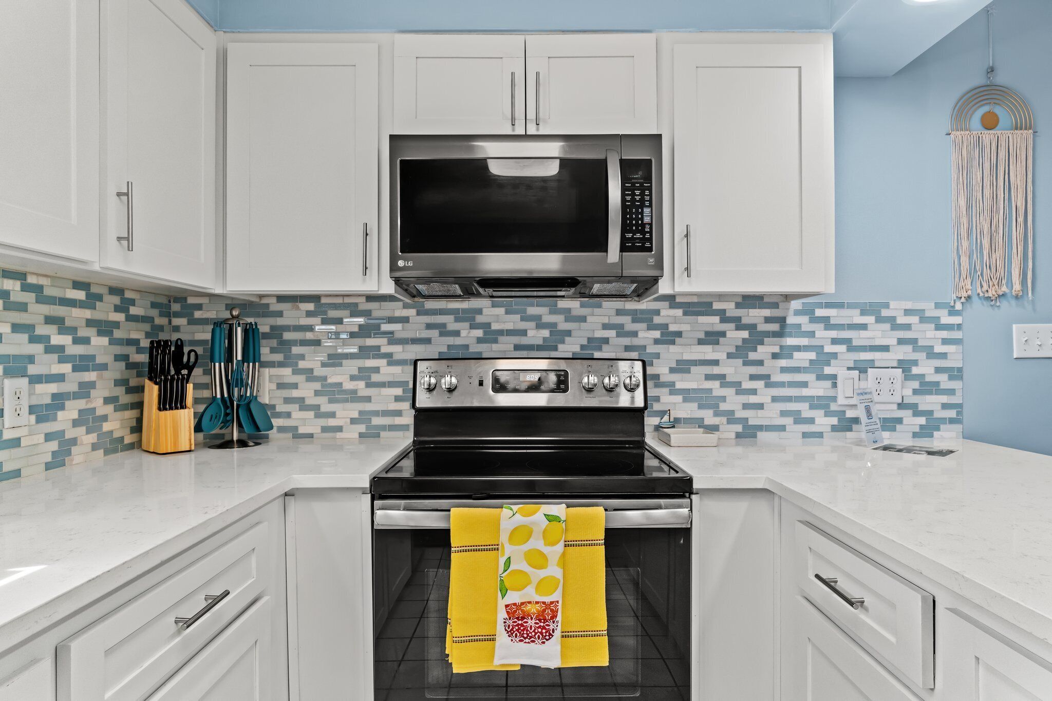 A kitchen with white cabinets, a black microwave, and a stainless steel oven.