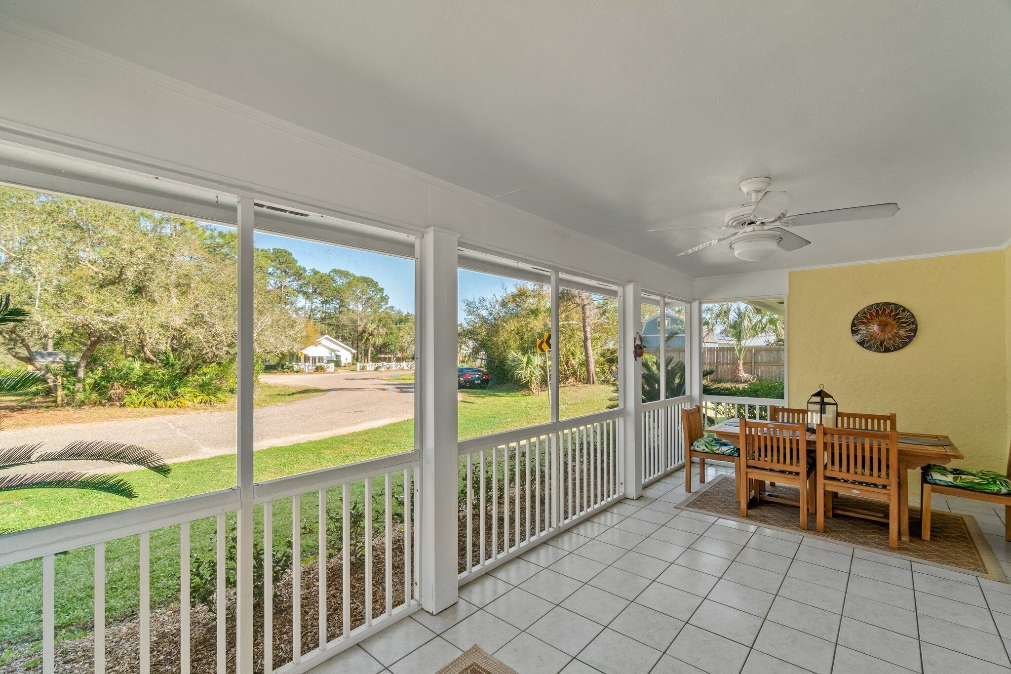 A covered patio with a white railing, a ceiling fan, and a table with chairs.