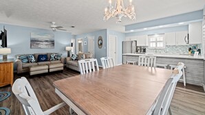 Un salón espacioso con una gran mesa de comedor de madera, un sofá beige y una araña.