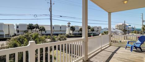 A wooden deck with a white railing, a blue chair, and a view of mobile homes and power lines.