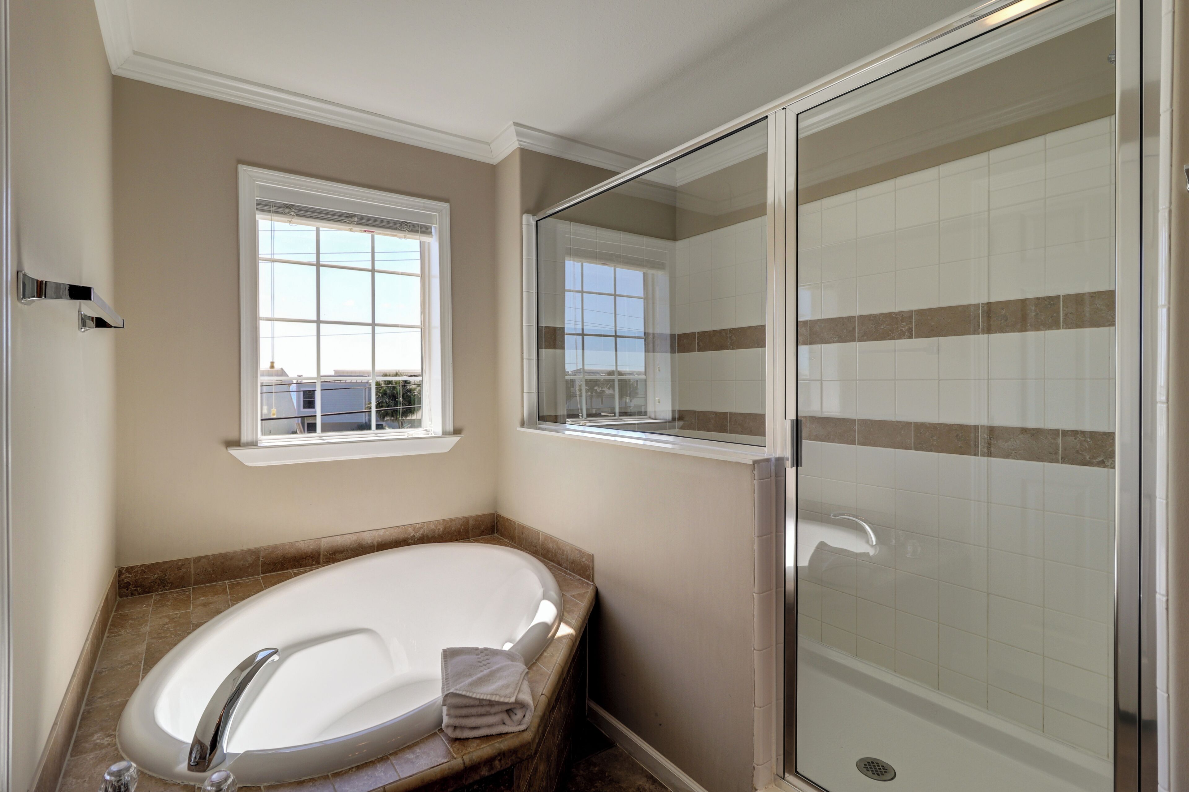 A bathroom with a freestanding bathtub, a glass-enclosed shower, and a window providing natural light.