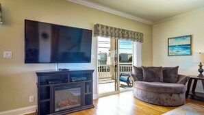 A living room with a flat-screen TV, a fireplace, a sofa, and a view to the outside. - Summer Dayz - Families Love It Here, Just Across From the Beach (Panama City Beach)