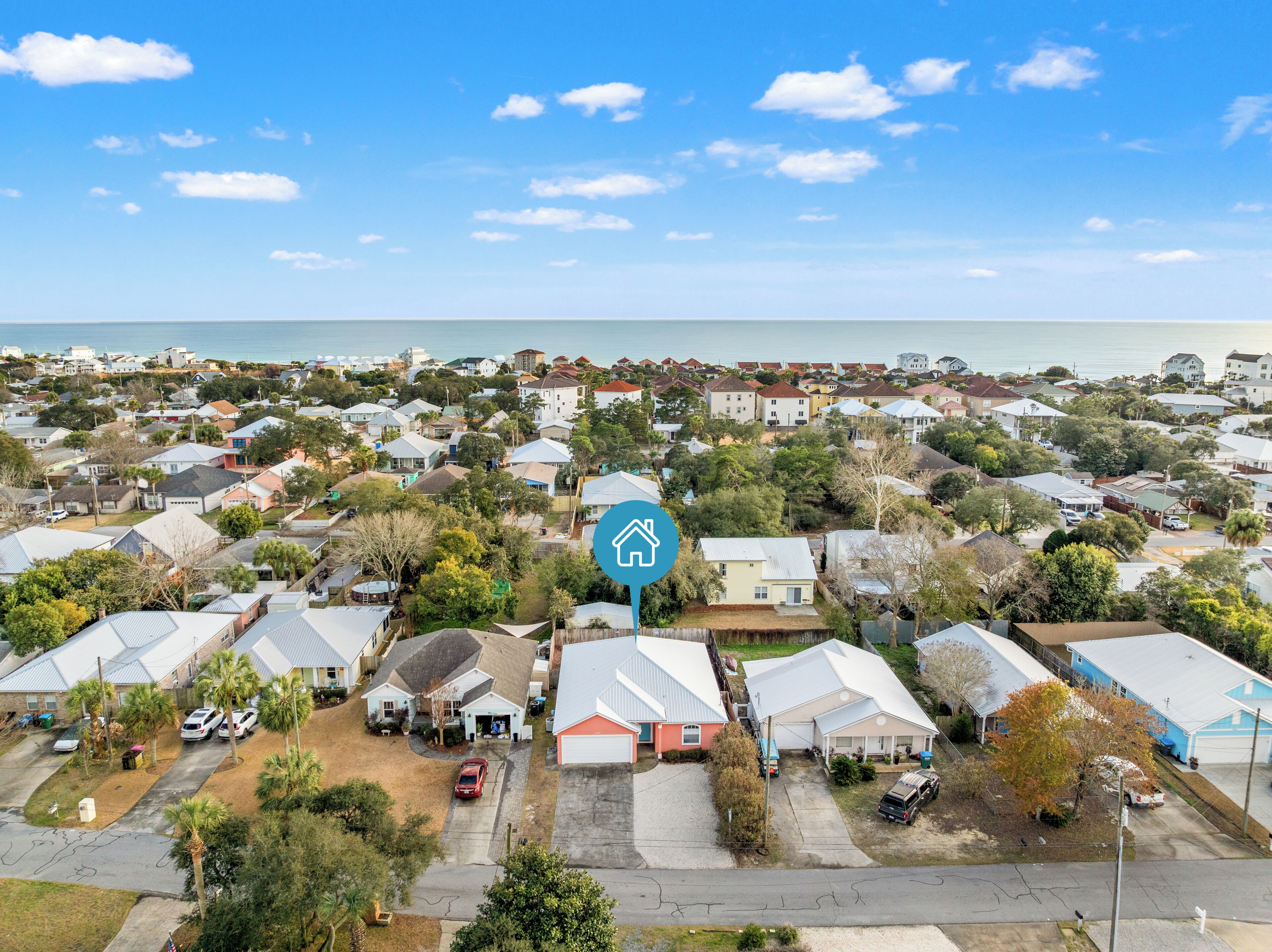 A residential area with houses, a clear sky, and a body of water in the background.