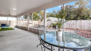 A covered patio with a glass table and chairs, a swing, and a view of the backyard. - Great Rates Available Now! / Relaxing Coastal Beach Home West PCB / 3Bd & 2Ba (Panama City Beach)