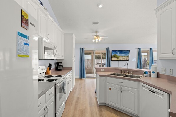 A modern kitchen with white cabinetry, a stove, and a sink.