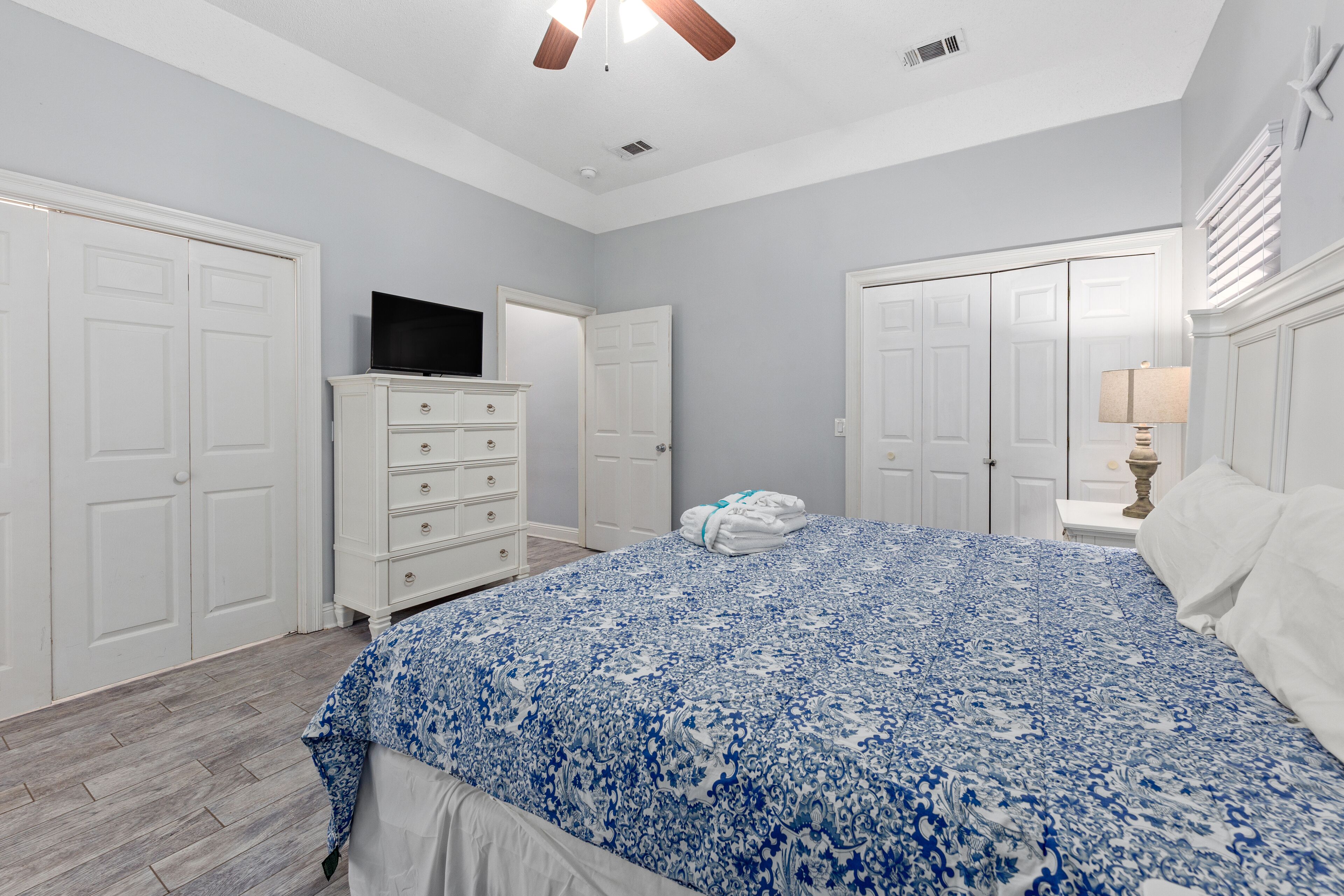 Une chambre à coucher avec un grand lit, une armoire blanche et un téléviseur posé sur une commode.
