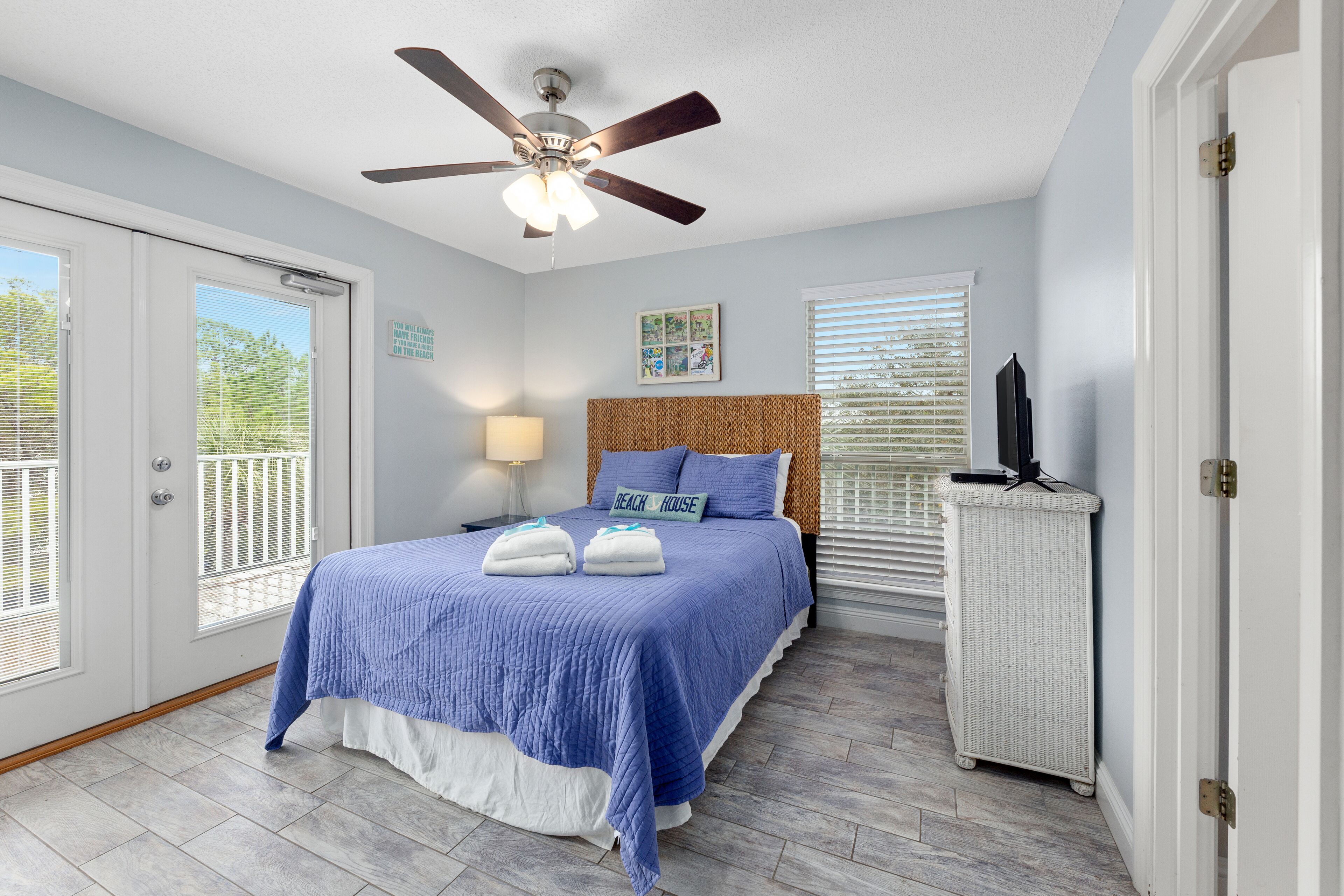 A bedroom with a bed, ceiling fan, and a white dresser.