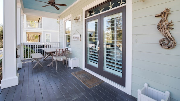 A covered porch with a ceiling fan, a table and chairs, and a welcome sign. - Four C's Retreat - Lavish Home With Private Boardwalk Access to the Beach (Santa Rosa Beach)