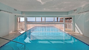An indoor swimming pool with clear views of the beach and ocean.
