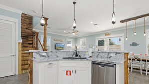 A modern kitchen with a granite countertop, white cabinetry, and a built-in dishwasher.