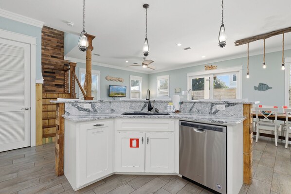 A modern kitchen with a granite countertop, white cabinetry, and a built-in dishwasher. - Three Master Bedrooms! Easy Beach Access! Gulf Views (Panama City Beach)