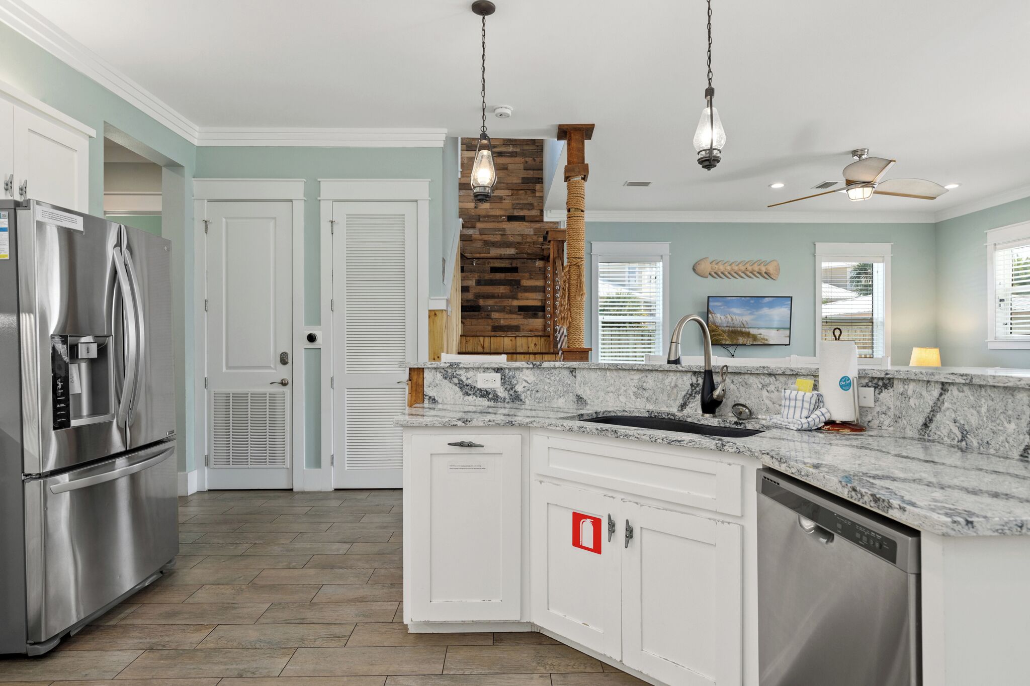 A modern kitchen with white cabinets, a stainless steel refrigerator, a built-in dishwasher, and a granite countertop.