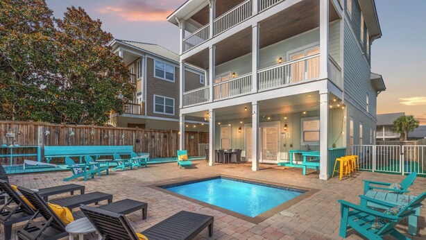 A multi-story building with a pool, outdoor seating, and a wooden fence.