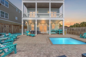 A two-story building with a covered patio area, a swimming pool, and outdoor seating.