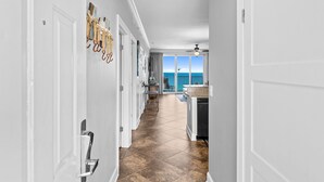 A hallway with a kitchen area, a dining area, and a view of the ocean. - Luxurious Ocean Villa Resort - Gulf Front Paradise With Views! (Panama City Beach)