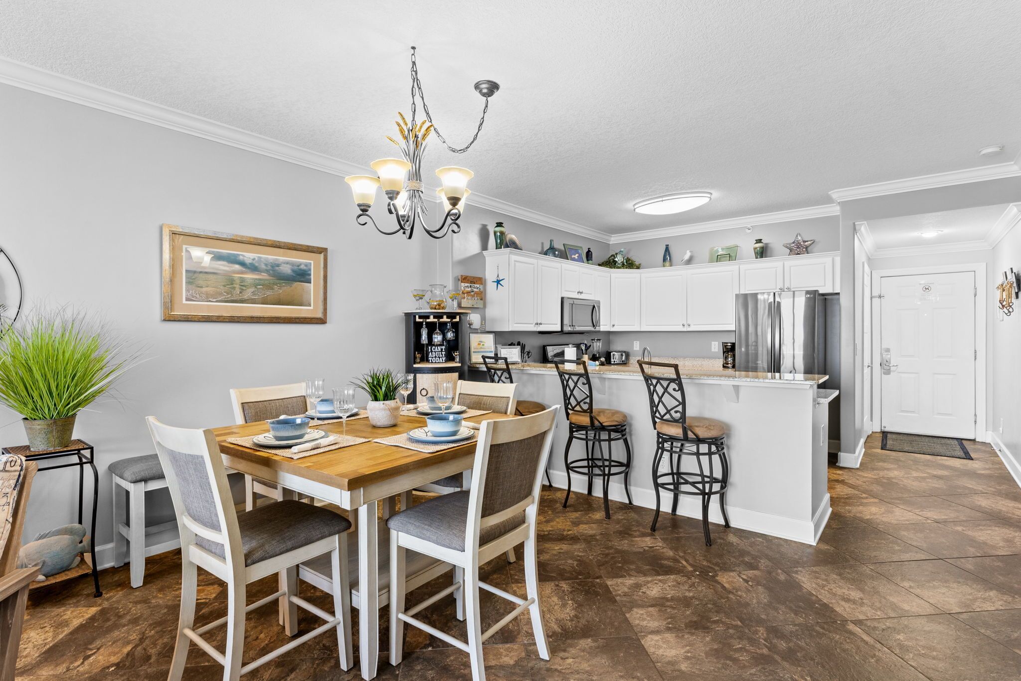 Cucina con mobili bianchi, tavolo da pranzo con sedie, un lampadario e vista sull'esterno.