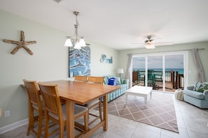 Relax in this spacious living area with a dining table, sofa, and coffee table, offering a balcony with ocean views.