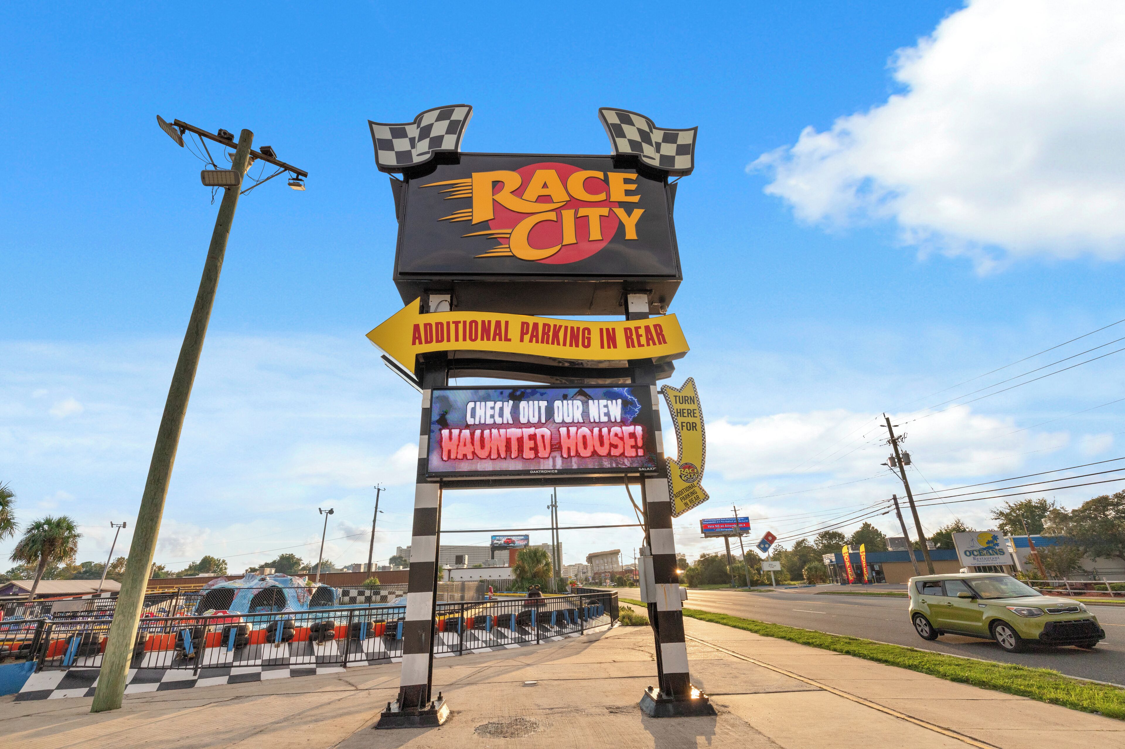 A sign for Race City with a haunted house advertisement.