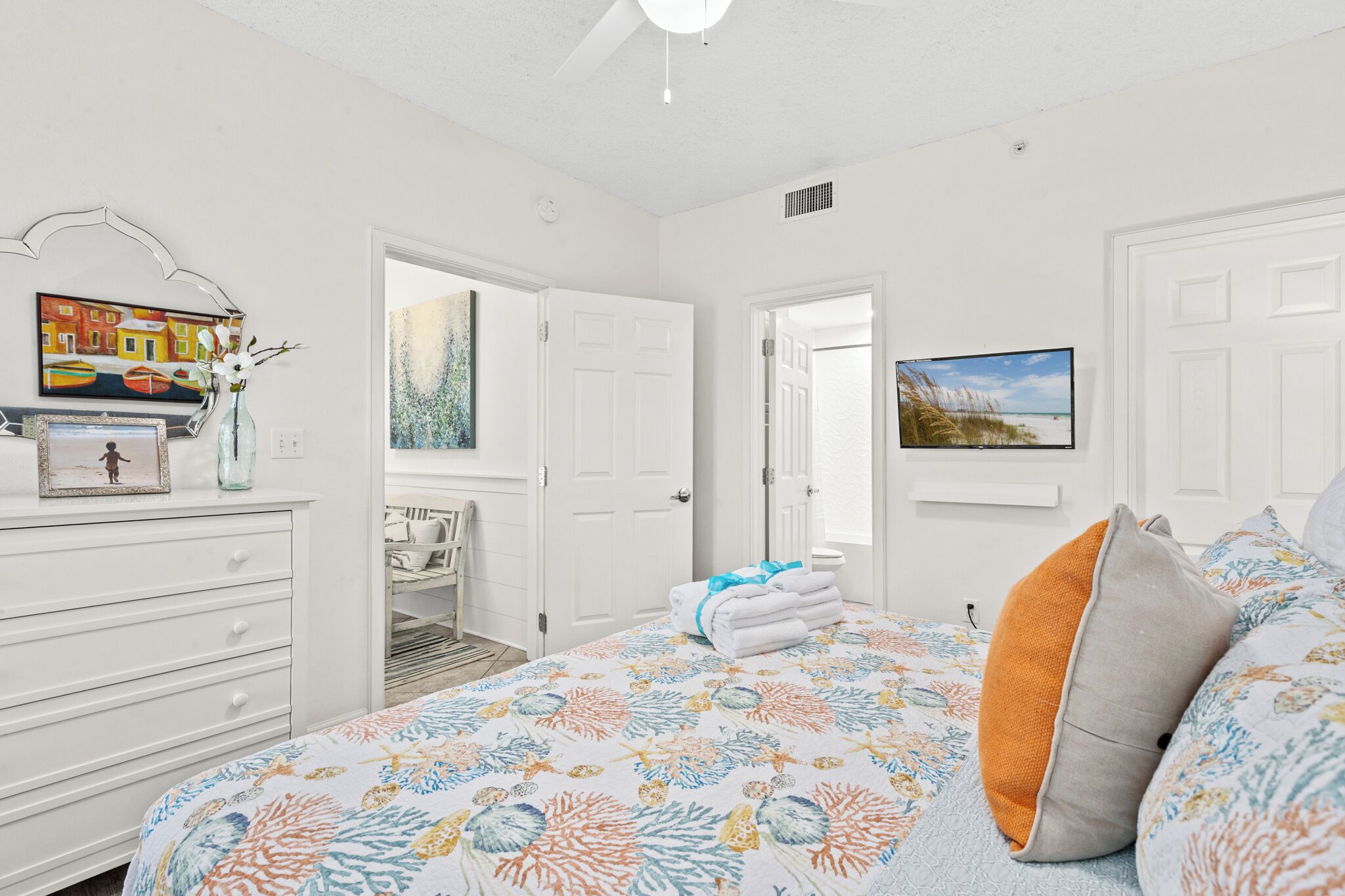 Un dormitorio con cama, cómoda, un cuadro y una puerta que da a otra habitación.
