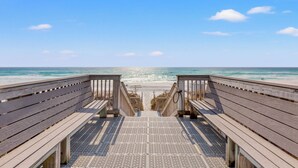 Ein Holzsteg führt zu einem Strand mit freiem Blick auf das Meer.