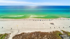 En strand med fri utsikt över havet, en sandstrand och några få personer samt parasoller.