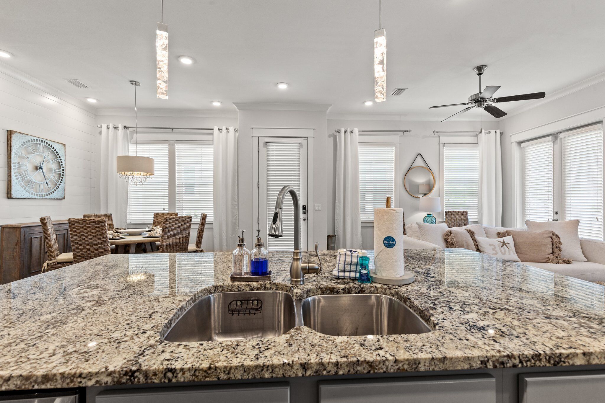 A modern kitchen with granite countertops, stainless steel sinks, and a dining area with wicker furniture.