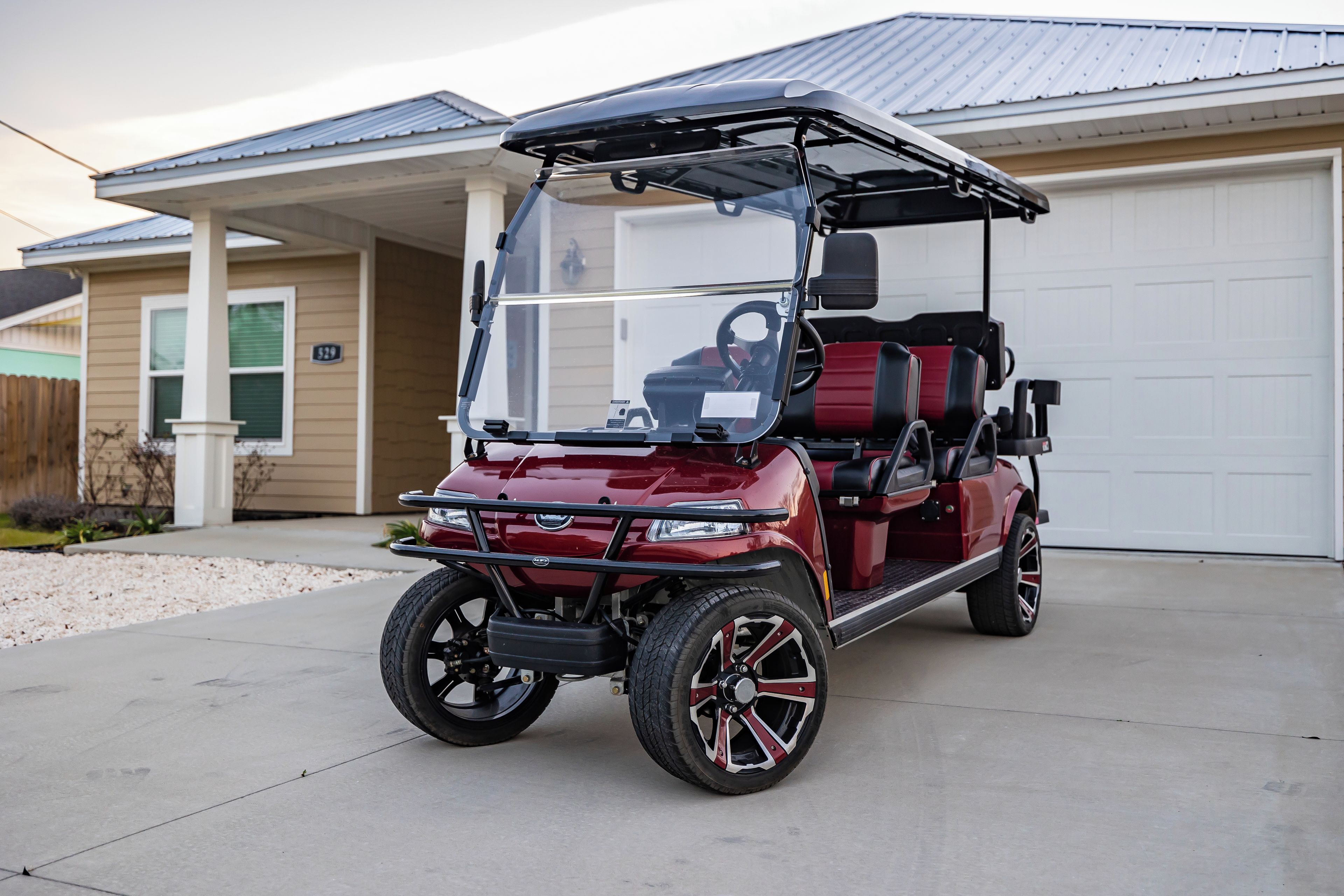 A red golf cart parked in front of a house with a garage.