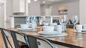 Ein Essbereich mit einem Holztisch, gedecktem Platz für vier Personen, weißen Tellern und klaren Weingläsern.