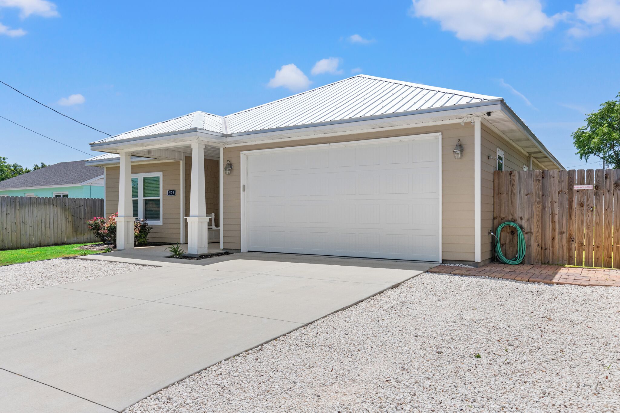 A single-story house with a covered porch, a garage, and a fenced backyard.