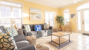 A living room with a sofa, coffee table, and a painting on the wall. - Across Street From Beach - Close to Pier Park - Sleeps 6! (Panama City Beach)