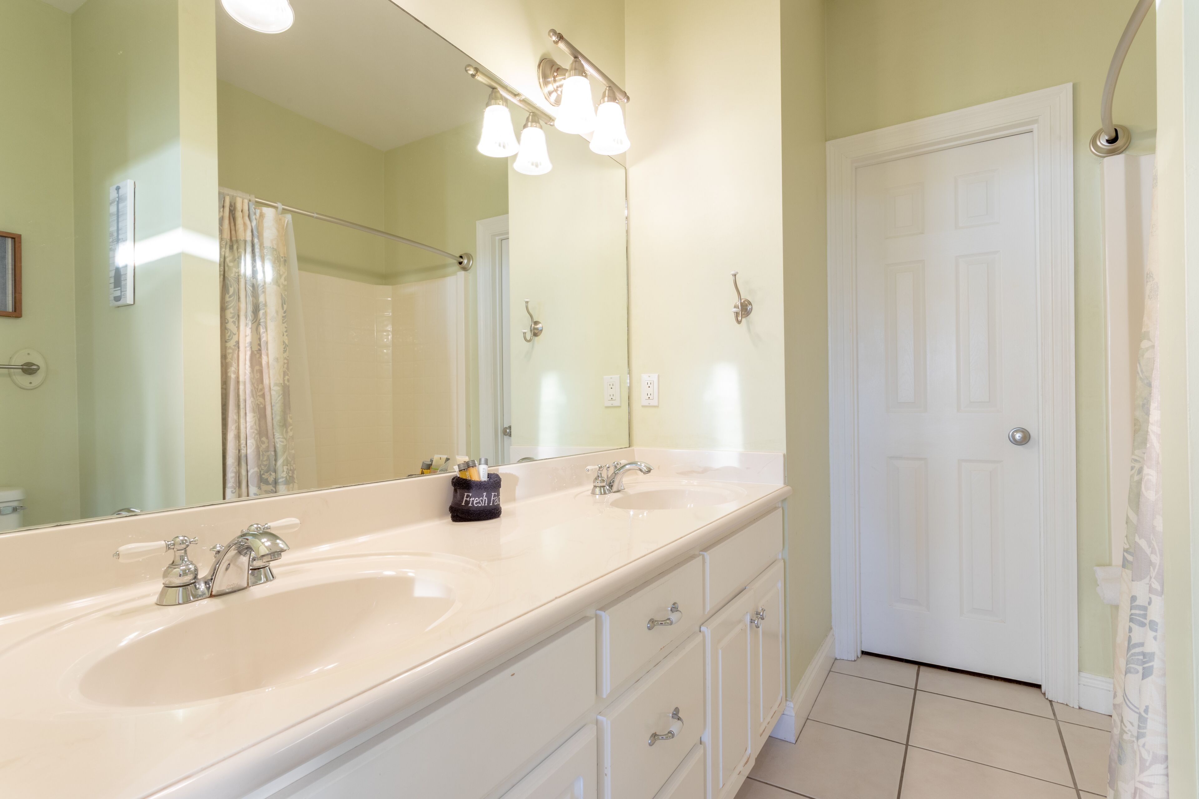 A bathroom with a double sink, a large mirror, and a white door.