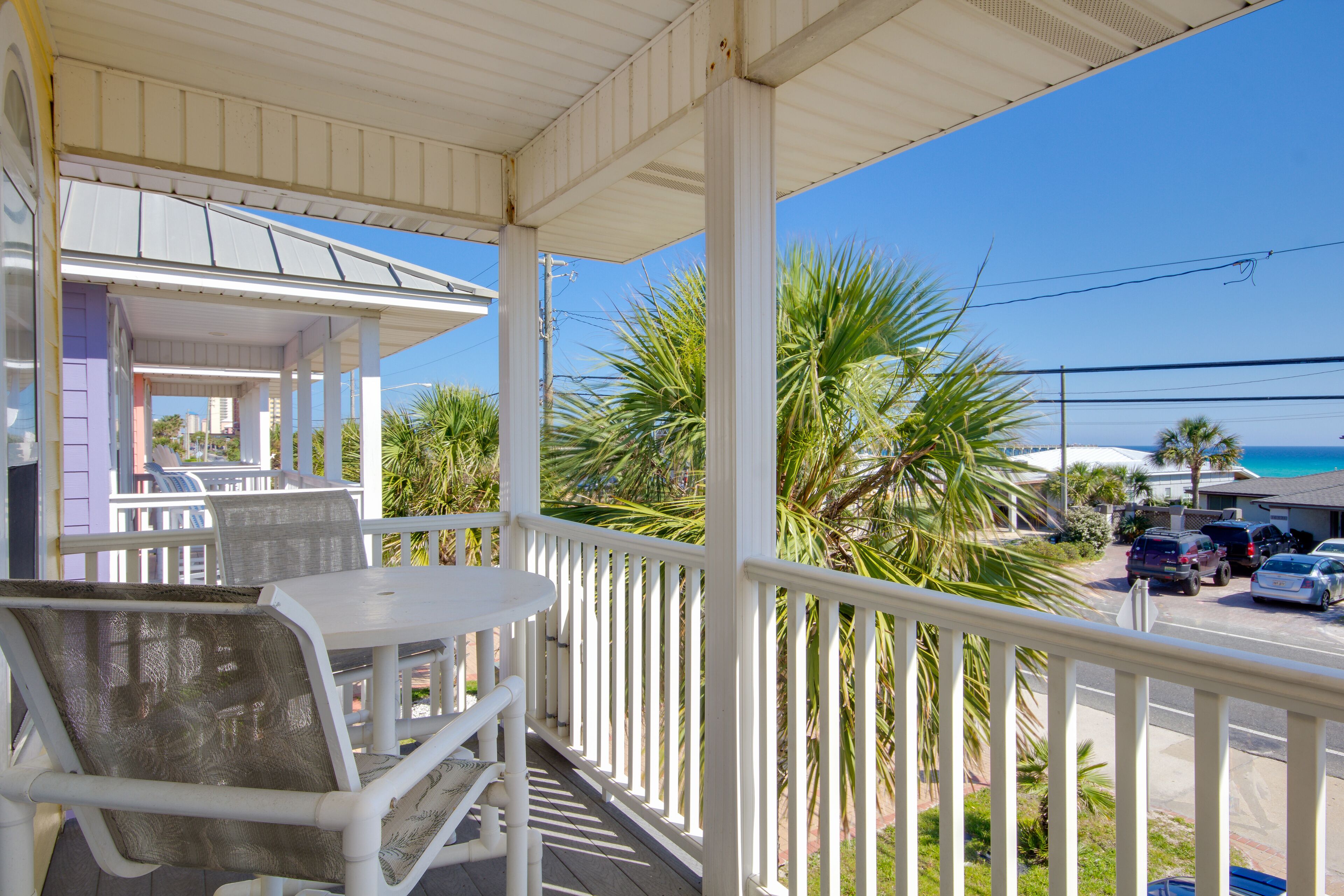 A covered outdoor seating area with white railings, a table, and chairs.