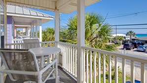 A covered outdoor seating area with white railings, a table, and chairs. - Across Street From Beach - Close to Pier Park - Sleeps 6! (Panama City Beach)